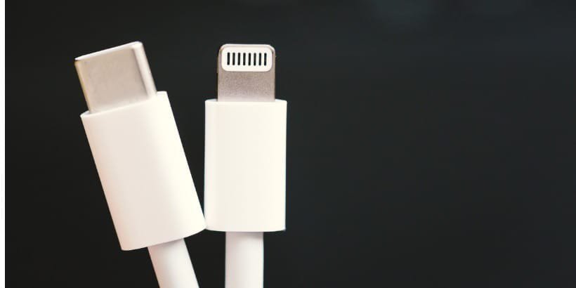 Dieses Bild zeigt eine Nahaufnahme von zwei weißen Ladekabeln, eines mit einem USB-C-Anschluss und das andere mit einem Lightning-Anschluss.