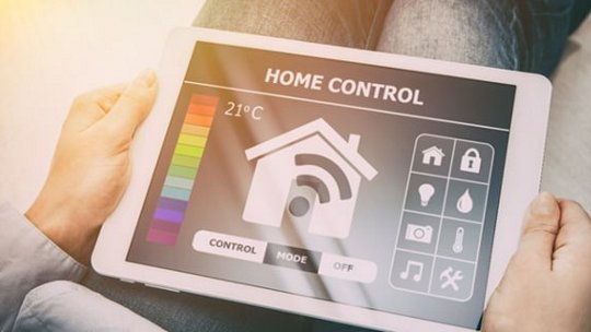 A tablet screen displays a smart home control interface with icons for temperature, lighting, and security. 