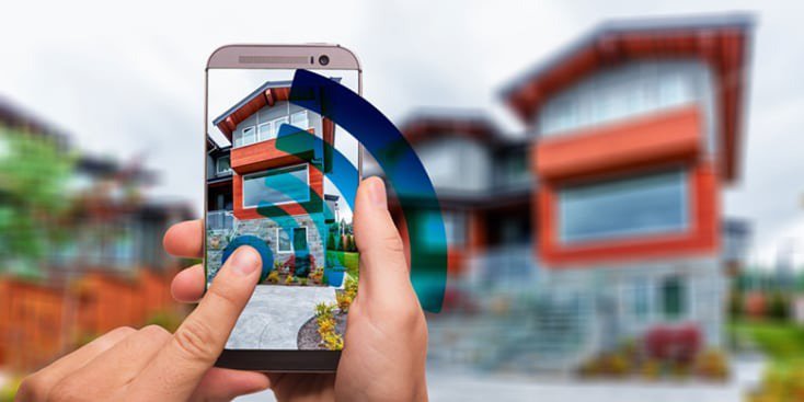 Un smartphone est tenu pour photographier une maison contemporaine avec des accents rouges et blancs.