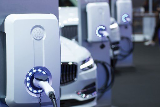 Close-up of modern electric vehicle charging stations connected to cars in a sleek indoor setting. 