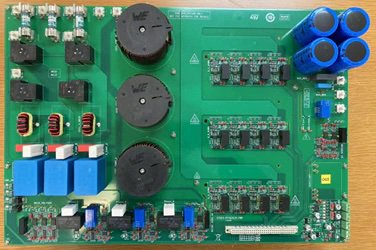 A detailed image of a green electronic circuit board featuring multiple blue capacitors, black cylindrical components, and various resistors and connectors.