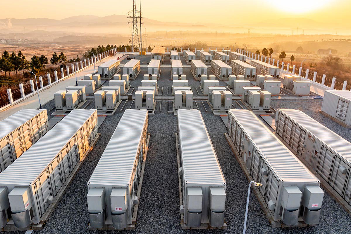 A large array of industrial container units is arranged in neat rows at an energy storage facility. 