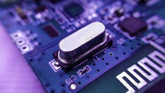 Una vista macro detallada de un componente electrónico plateado en una placa de circuito azul.