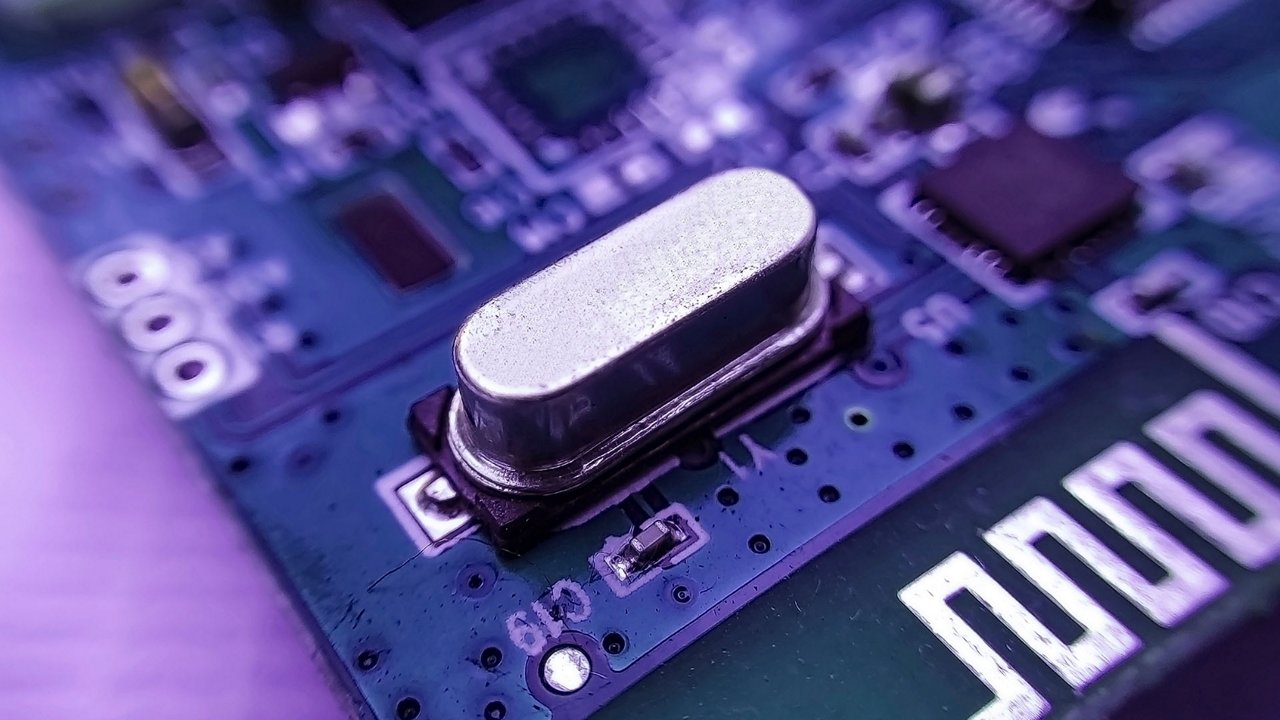 Una vista macro detallada de un componente electrónico plateado en una placa de circuito azul.