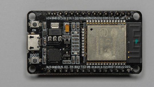 ESP32开发板的顶视图，显示ESP32模块、USB连接器、板载按钮和标有标签的引脚头，背景为灰色。
