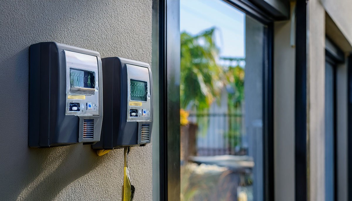 Two electronic access control units are mounted on an exterior wall beside a large glass door or window.