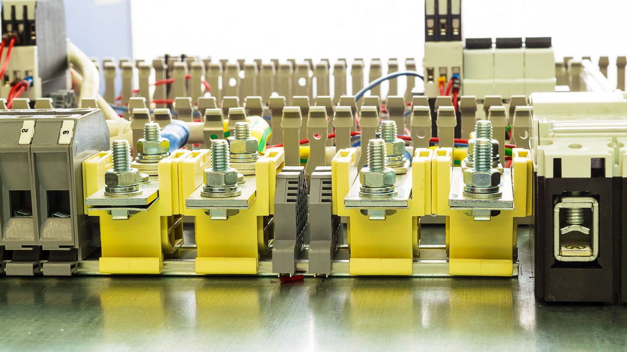 Closeup view of an industrial electrical terminal block assembly with multiple yellow connectors and large metal bolts