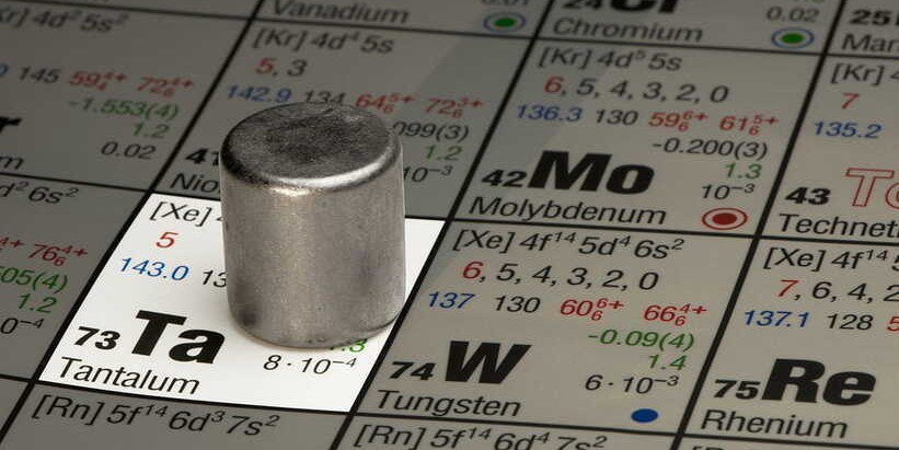 一个实心金属圆柱体放置在元素周期表上，特别强调元素钽（Ta），原子序数73。