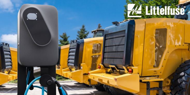 A Littelfuse electric vehicle charger is prominently displayed in the foreground, featuring a sleek design and visible charging cables. The background showcases large yellow construction vehicles parked outdoors under a clear sky. The Littelfuse logo is clearly visible in the top-right corner of the image.