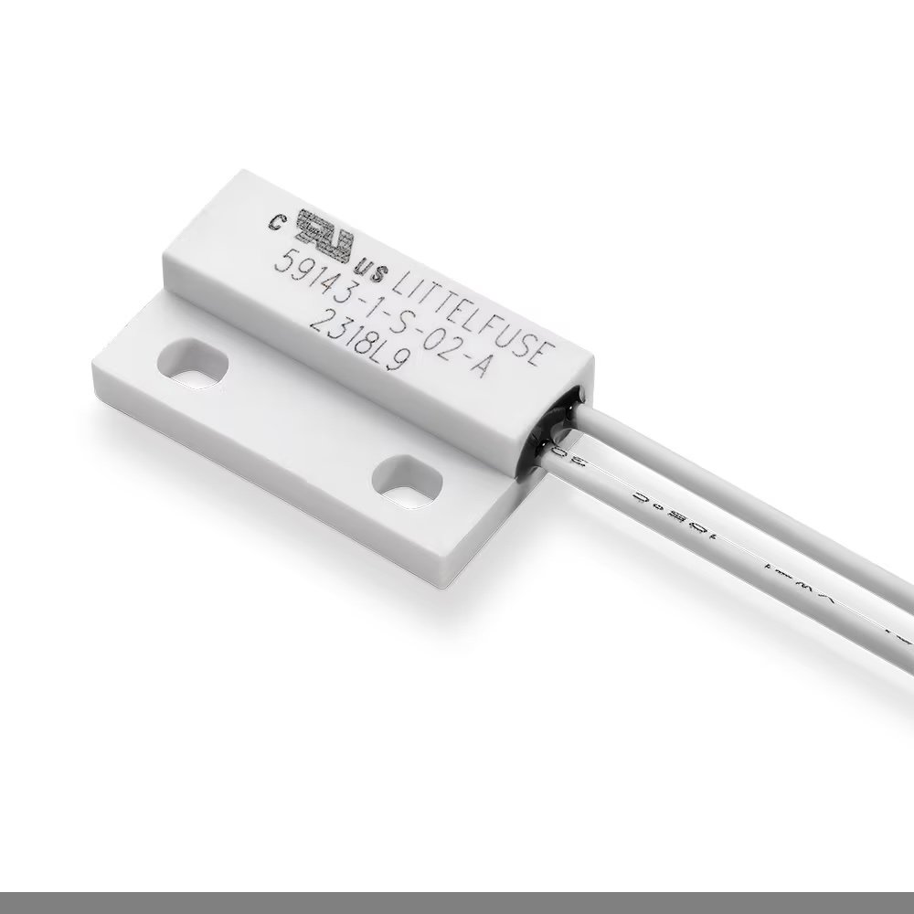 A Littelfuse magnetic sensor, model 59143-1-S-02-A, is shown in closeup against a white background. The device features a rectangular white housing with two mounting holes and attached white wires.