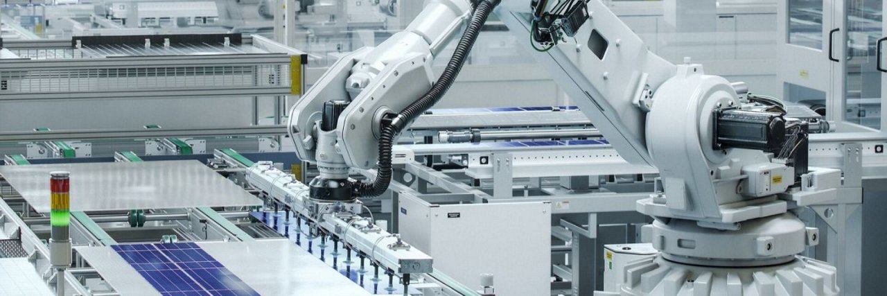 A robotic arm places a cardboard box onto an autonomous mobile robot in a modern warehouse setting