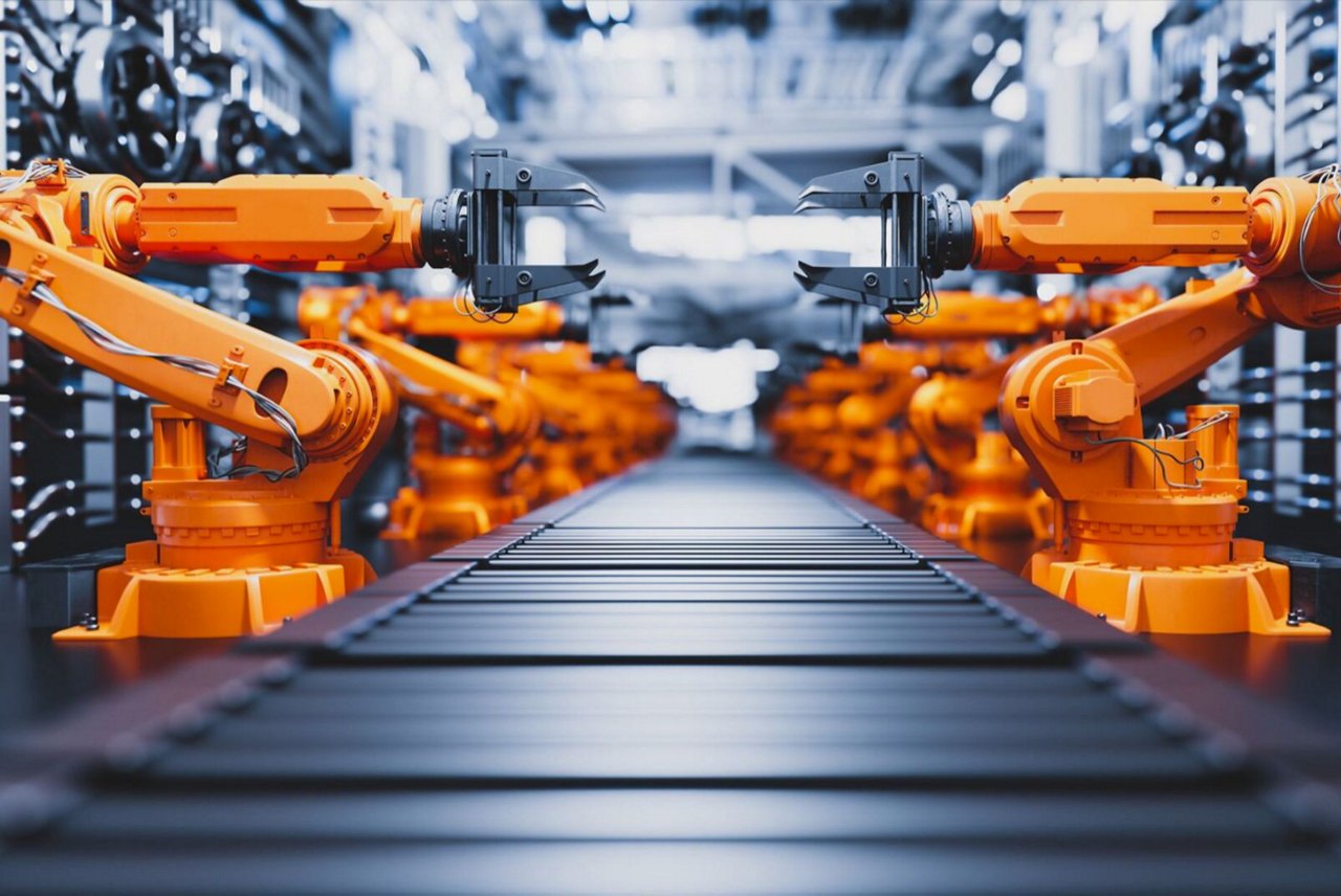 La imagen muestra varios brazos robóticos naranjas posicionados a lo largo de ambos lados de una cinta transportadora en un entorno industrial de alta tecnología.