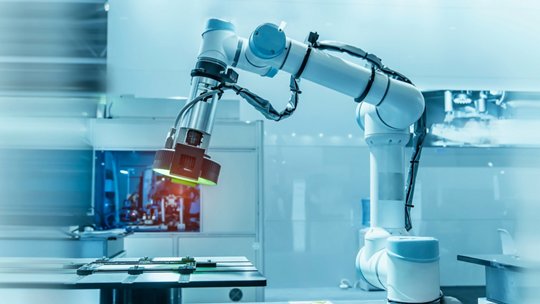 Se muestra un brazo robótico industrial moderno inspeccionando de cerca una placa de circuito verde en un entorno de fabricación de alta tecnología.