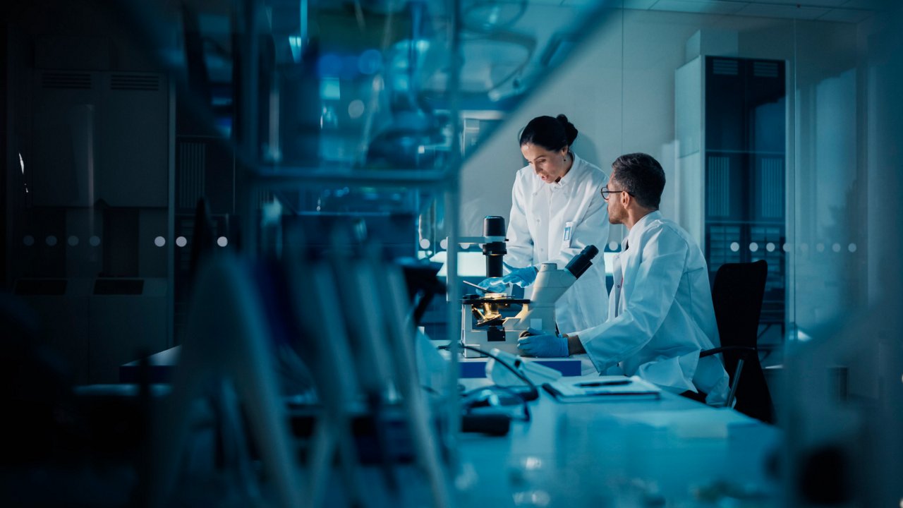 Two scientists in white lab coats work together in a high-tech laboratory. 