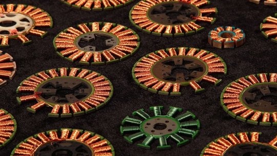 多个圆形电机定子带有铜线绕组，展示在深色纹理背景上。