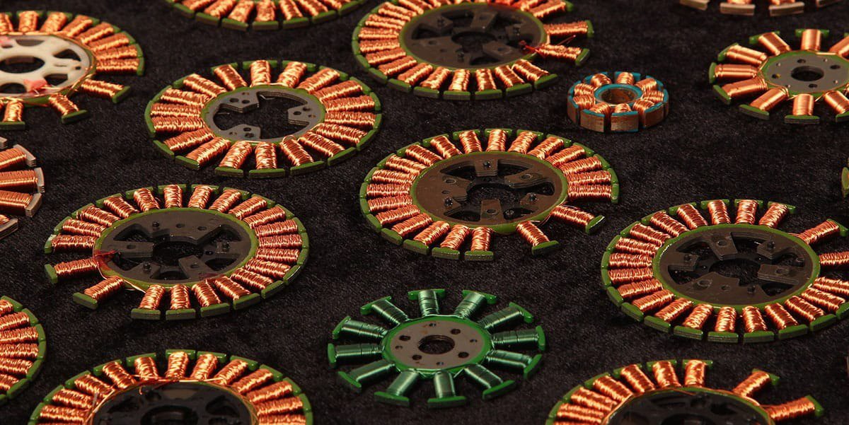 多个带有铜线绕组的圆形电机定子展示在深色纹理背景上。