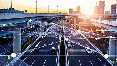A modern highway in an urban setting is depicted with digital connection overlays symbolizing smart city technology. 