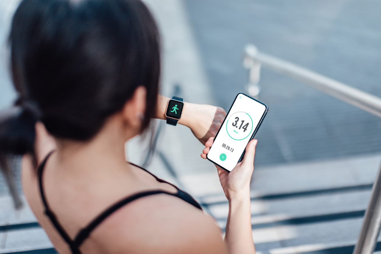 A young woman in athletic wear checks her smartphone displaying a fitness app