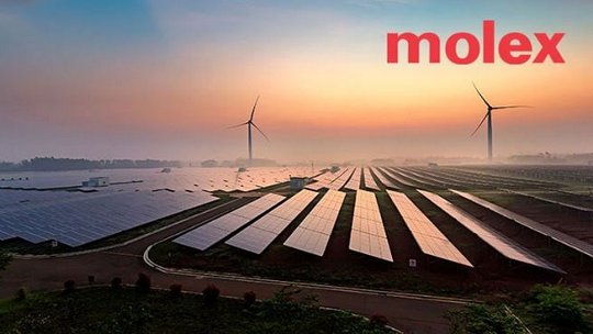 Une vaste ferme solaire, composée de rangées de panneaux photovoltaïques, s'étend à travers le paysage, accompagnée d'éoliennes en arrière-plan. Le décor est éclairé par un lever de soleil vibrant, créant une scène apaisante axée sur une énergie durable. Le texte 'molex' est clairement visible dans le coin supérieur droit.
