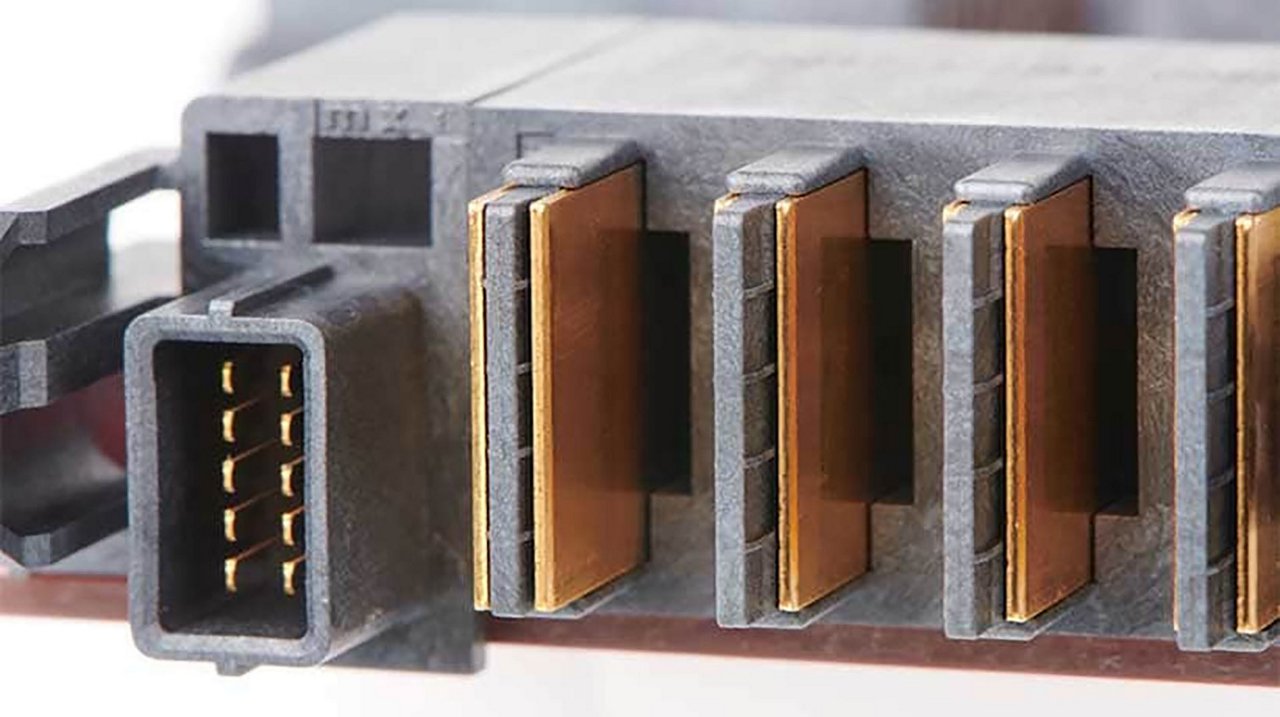 Close-up of a circuit board connector with copper contact strips and gold-plated pins.
