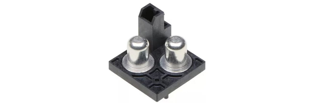 Close-up of a dual-pin electrical connector featuring two metallic pins mounted on a black plastic base. 