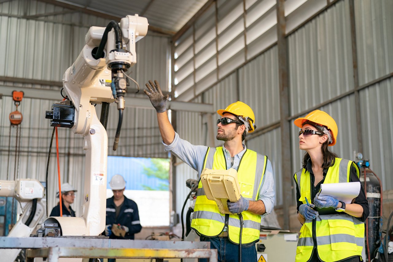 Robotics engineer working on maintenance of modern robotic arm in factory warehouse