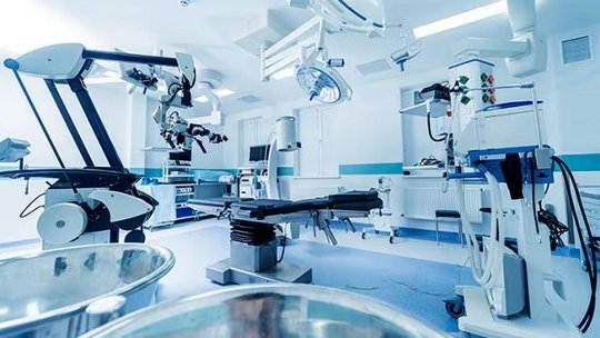 Es wird ein hochmodernes Operationssaal gezeigt, das fortschrittliche chirurgische Ausrüstung und Roboterarme umfasst.