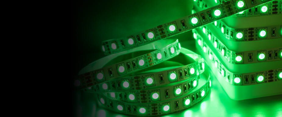 Close-up of green LED light strips coiled and stacked, glowing brightly against a dark background.
