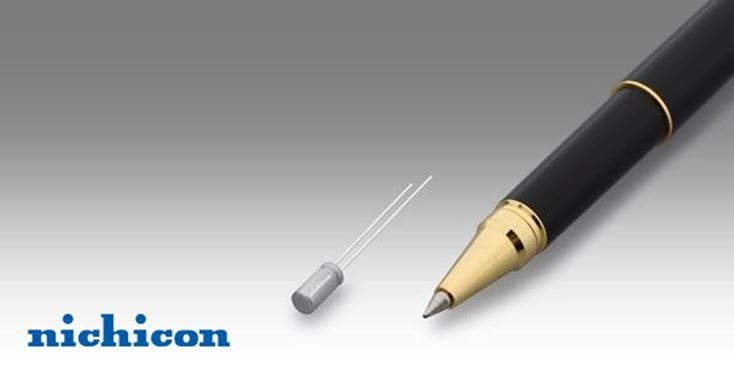 一只带有金色装饰的黑色钢笔旁边展示着一个小型的日化(Nichicon)电容器。