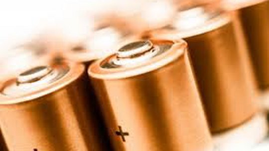 A detailed view of multiple cylindrical batteries with copper tops arranged in a row.