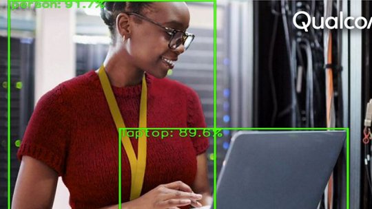 A person wearing a red sweater and yellow lanyard is seen working on a laptop in a server room.