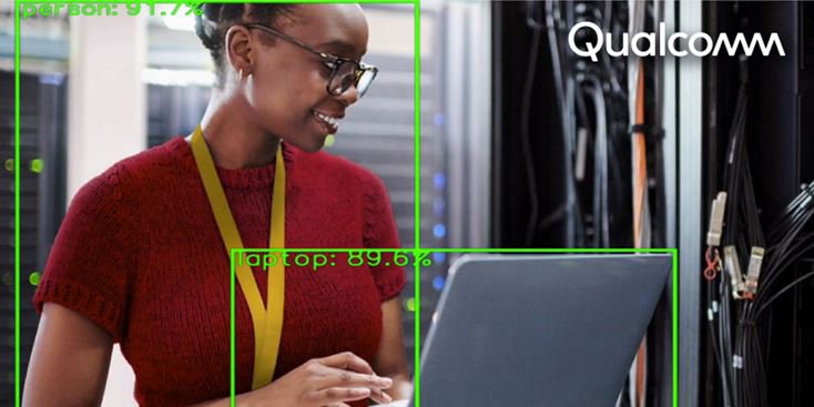 A person wearing a red sweater and yellow lanyard is seen working on a laptop in a server room.