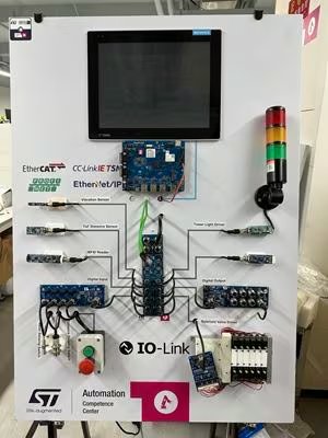 This image shows an industrial automation demonstration board featuring a large display screen, multiple circuit boards, and a vertical signal tower light. The board is labeled with various industrial communication protocols such as EtherCAT, CC-Link IE TSN, and IO-Link.