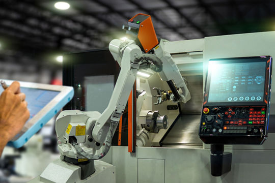 A robotic arm is actively working on a CNC machine in a modern industrial setting. 