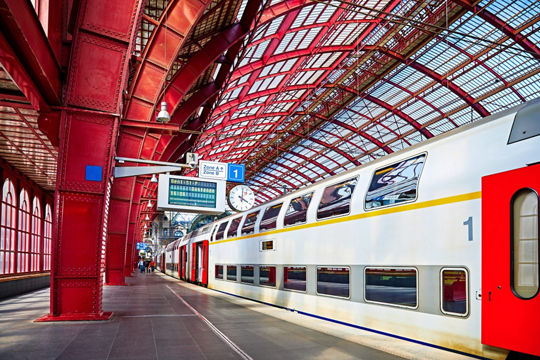 A sleek double-decker train is stationed at a platform in Antwerp's iconic railway station..