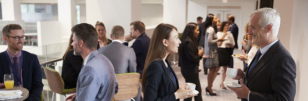 A group of business professionals engaged in networking and conversations during a corporate event.
