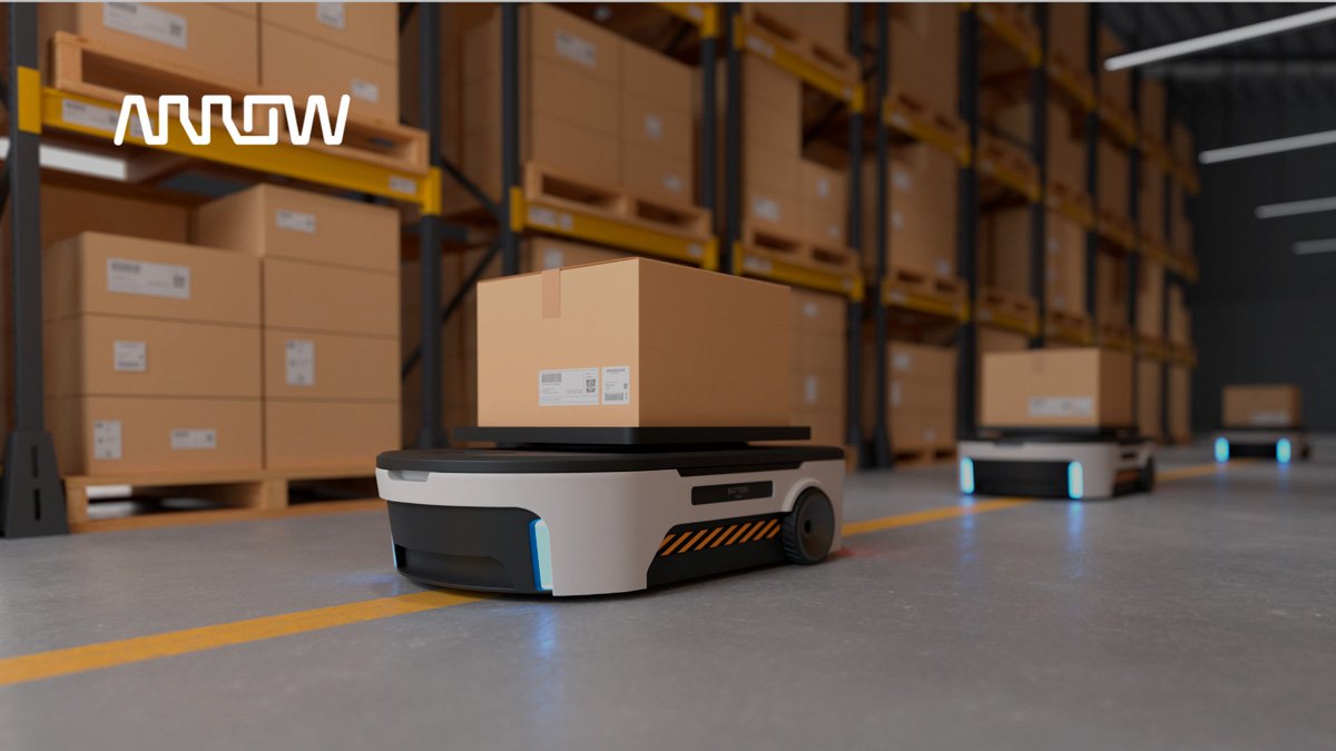 Autonomous mobile robots carry large cardboard boxes across a modern warehouse floor. 