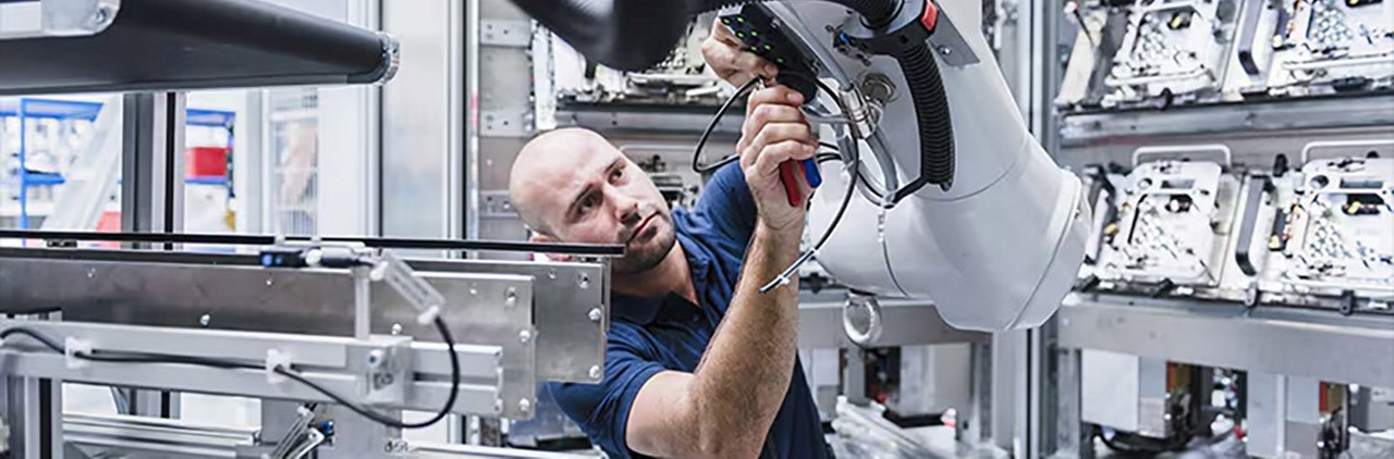 一名技术员在高科技工业环境中操作机械臂。