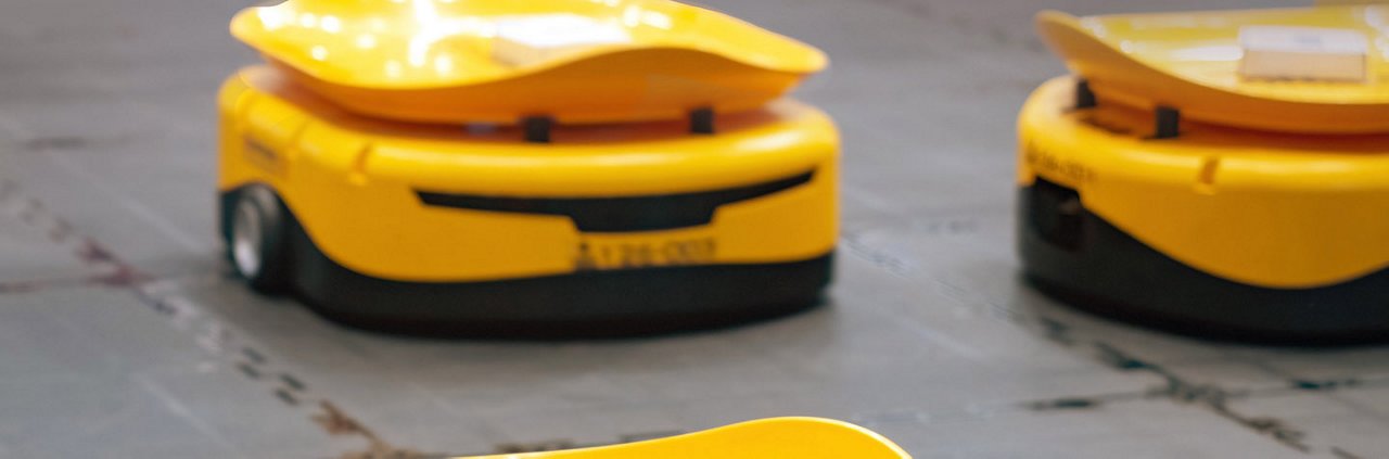 在仓库环境中可以看到两个黄色的自动机器人，设计用于物料搬运或物流。