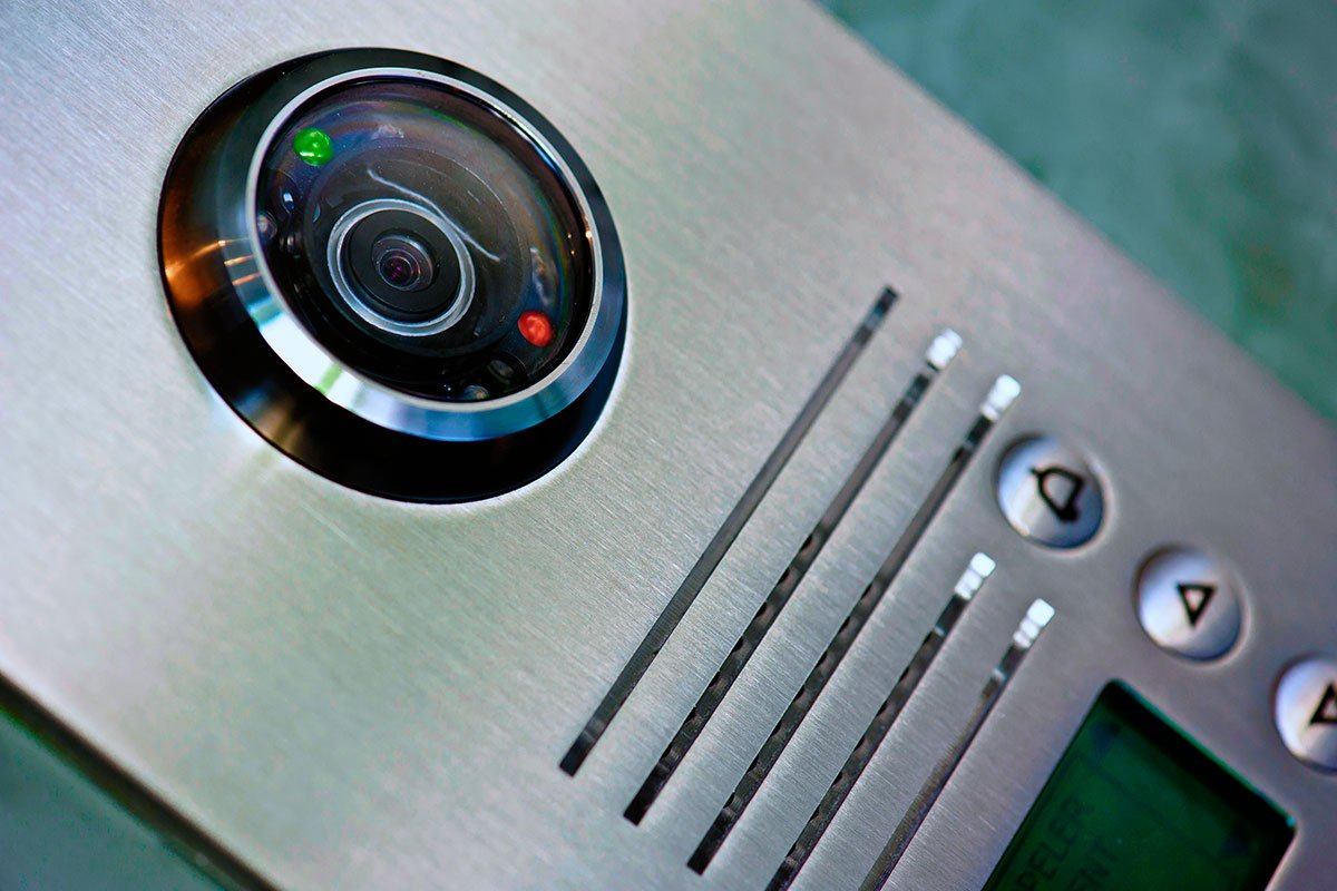 Close-up of a modern video intercom system mounted on a stainless steel panel. 