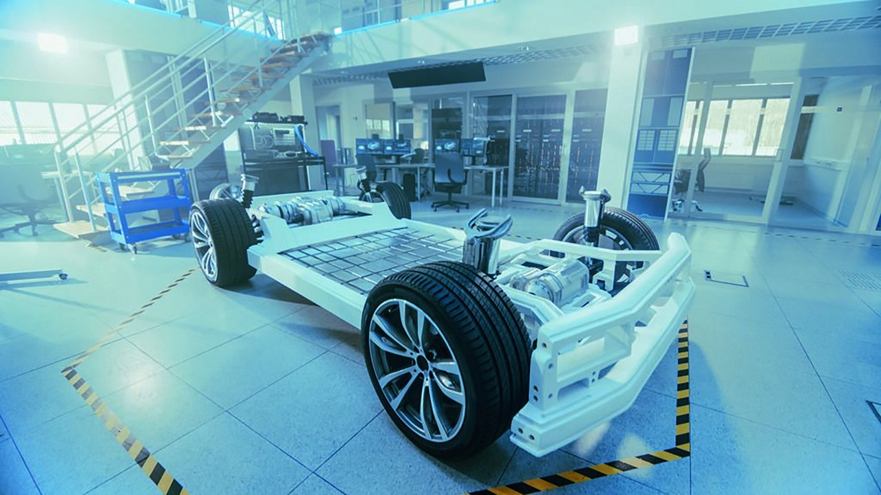 A detailed view of an electric vehicle chassis displayed in a high-tech automotive workshop. 