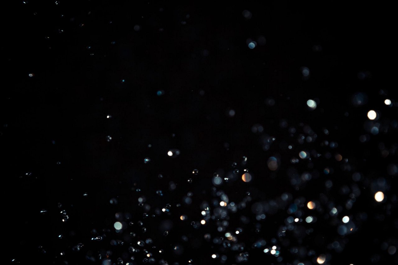 A visually striking abstract image featuring scattered light bokeh against a dark background