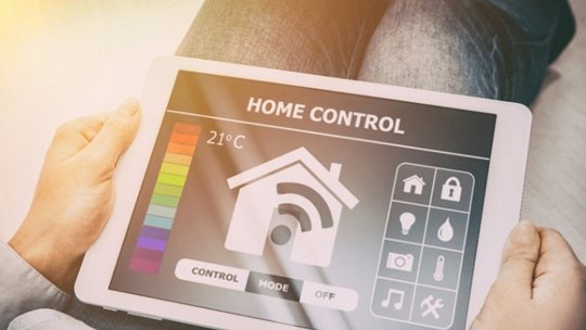 A person holds a tablet showcasing a smart home control interface