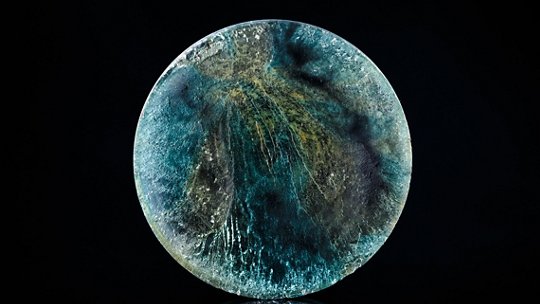 El tema principal es un objeto redondo y abstracto con patrones ondulantes en azul, verde y toques de amarillo.