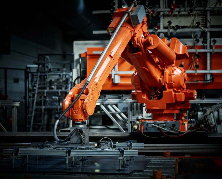 Un bras robotique industriel orange fonctionne dans une installation de fabrication moderne.