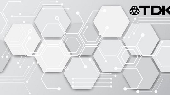 Un design futuriste présentant des motifs hexagonaux blancs sur un fond gris clair. Le logo TDK est affiché de manière proéminente dans le coin supérieur droit, ajoutant un élément de marque technologique. Le visuel évoque une esthétique moderne et épurée avec des connexions semblables à des circuits.