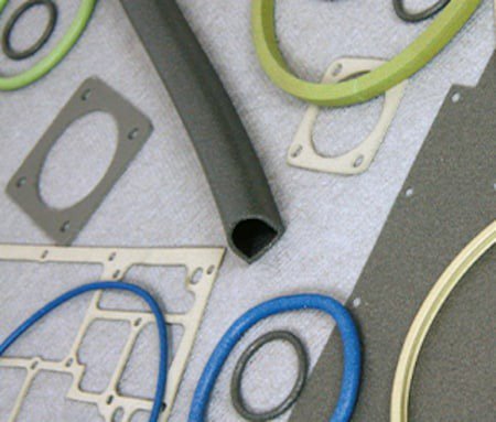 A collection of various industrial gaskets and seals displayed on a textured surface.