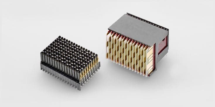 Two compact electronic heat sinks are displayed against a neutral gray background. The designs feature metallic fins arranged vertically and horizontally for efficient heat dissipation. The left unit has a darker finish, while the right unit showcases a combination of silver and gold tones. These components are essential for thermal management in electronic devices.