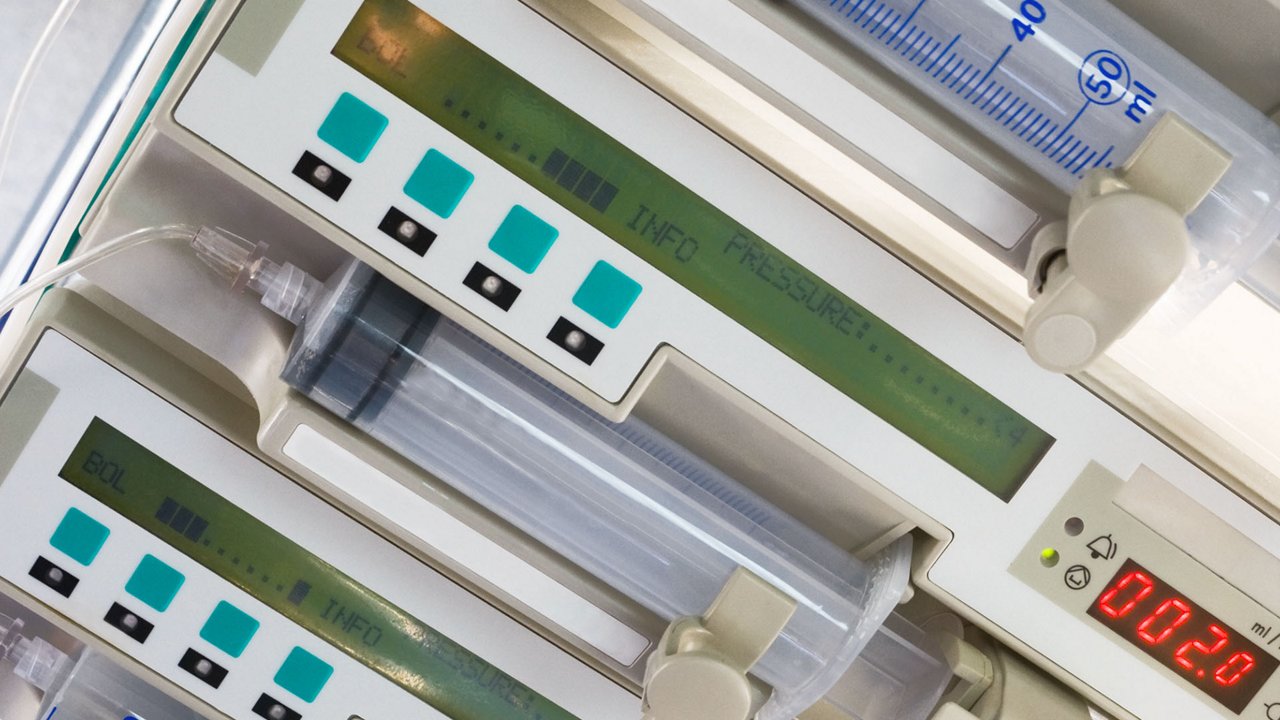Close-up of medical infusion pumps featuring digital screens and syringe mechanisms. 