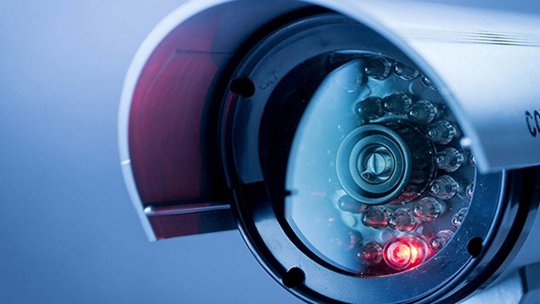 A close-up view of a modern security camera lens with visible infrared LEDs.